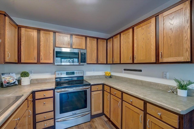 kitchen featuring light countertops, dark wood-style floors, brown cabinets, and appliances with stainless steel finishes