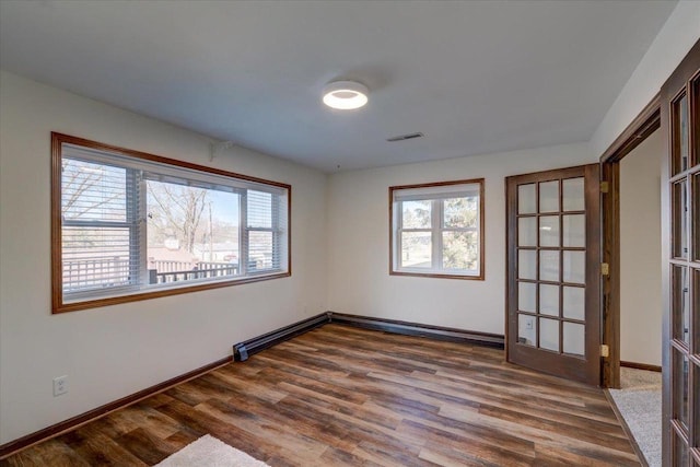 spare room with visible vents, baseboards, and dark wood-style floors