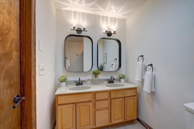 full bathroom featuring double vanity, toilet, tile patterned floors, and a sink