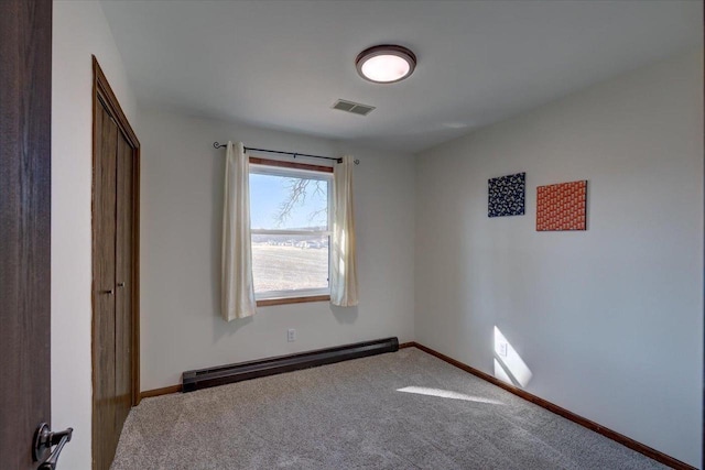 unfurnished bedroom with a baseboard heating unit, carpet, visible vents, and baseboards