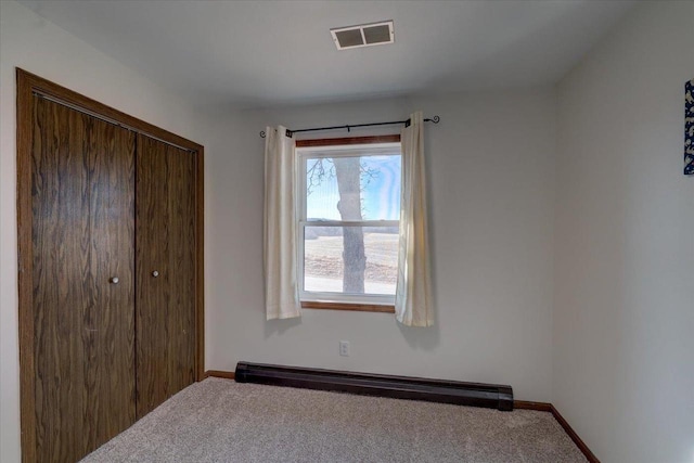 unfurnished bedroom with a closet, carpet flooring, visible vents, and baseboard heating