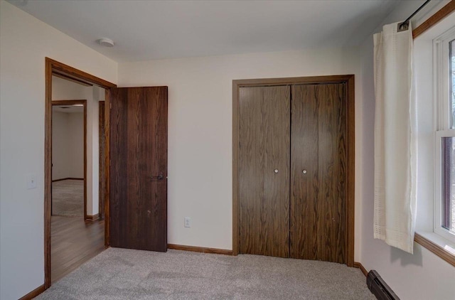 unfurnished bedroom with multiple windows, light colored carpet, a closet, and baseboards