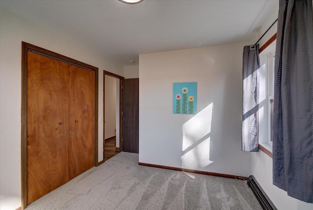 bedroom with a closet, carpet flooring, and a baseboard heating unit