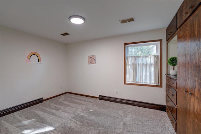 spare room with visible vents, carpet flooring, a baseboard heating unit, and baseboards