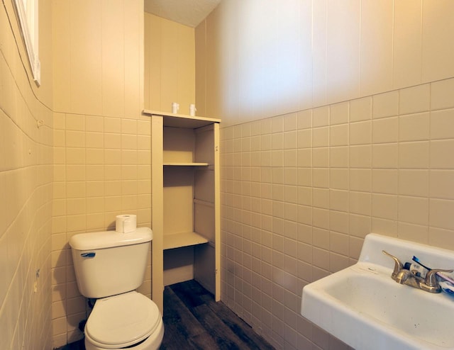 bathroom featuring a sink, tile walls, and toilet