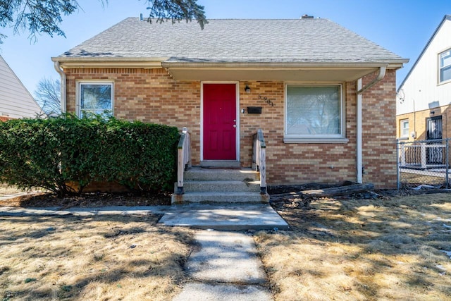 view of front of home with a shingled roof and brick siding