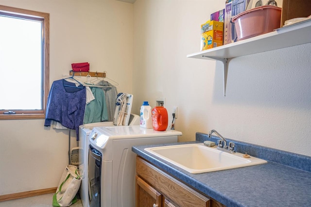 clothes washing area with baseboards, a sink, cabinet space, and washer and dryer