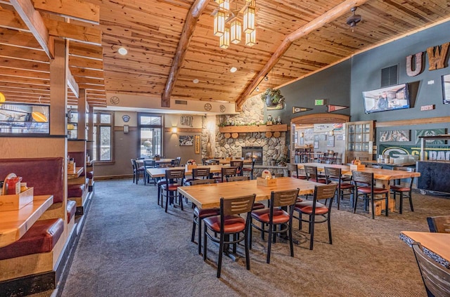 dining room with high vaulted ceiling, carpet, wood ceiling, and a stone fireplace