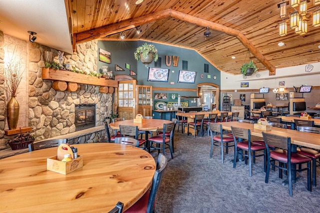 carpeted dining area with high vaulted ceiling, a stone fireplace, wooden ceiling, and beam ceiling