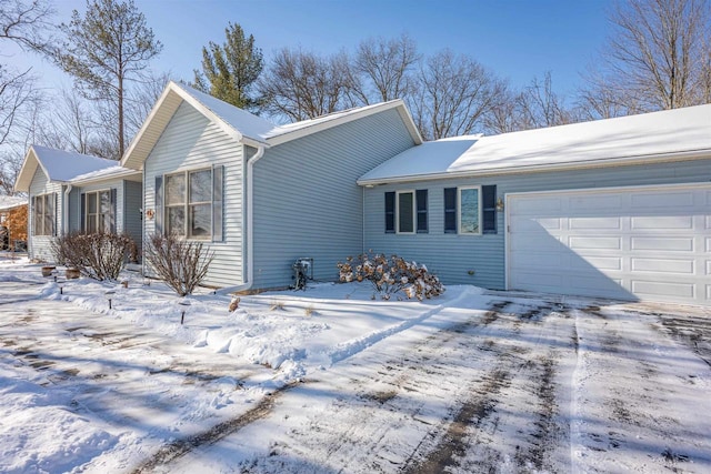 view of snowy exterior with driveway and an attached garage