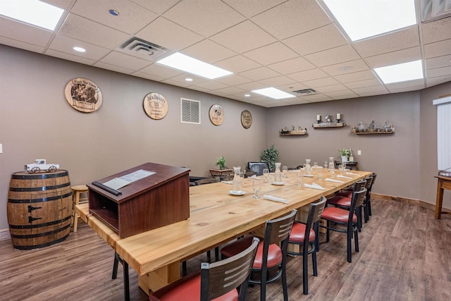 dining room featuring baseboards, visible vents, a drop ceiling, and wood finished floors