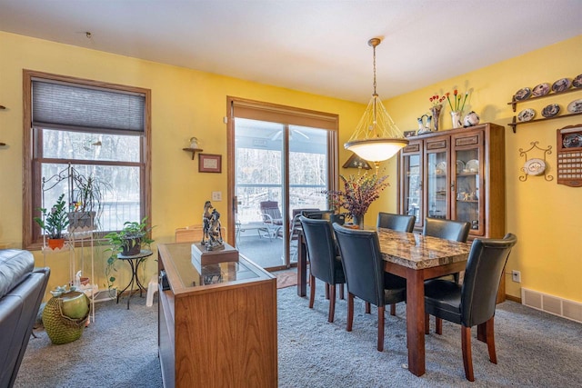 carpeted dining area featuring visible vents and baseboards