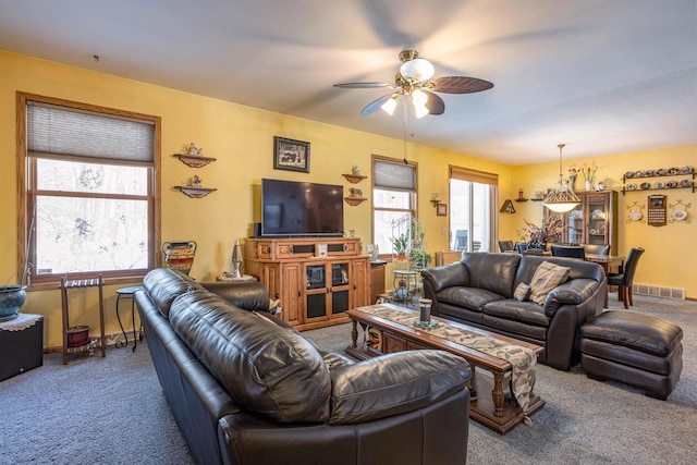 carpeted living room with a ceiling fan, baseboards, visible vents, and a wealth of natural light