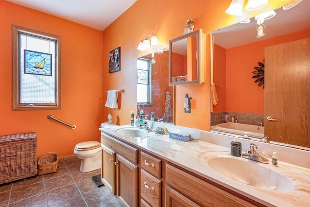 bathroom with a garden tub, a sink, toilet, and double vanity