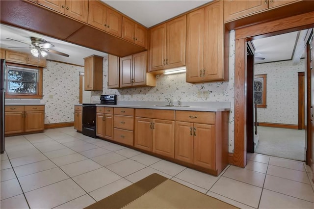 kitchen featuring light tile patterned floors, black range with electric cooktop, a sink, light countertops, and wallpapered walls