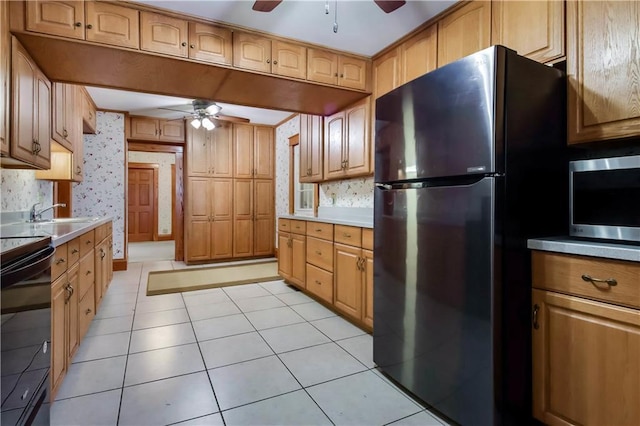 kitchen with wallpapered walls, stainless steel microwave, freestanding refrigerator, light countertops, and a sink