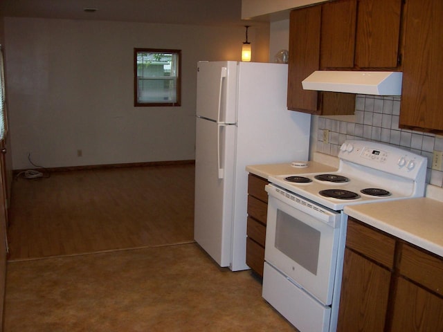 800 Thompson St, Portage, WI 53901 - kitchen with white appliances, under cabinet range hood, brown cabinetry, light countertops, and decorative backsplash
