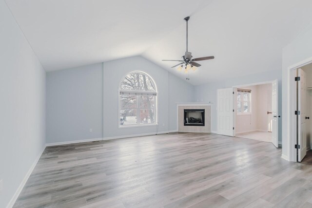 unfurnished living room with vaulted ceiling, ceiling fan, a fireplace, and light wood-style floors