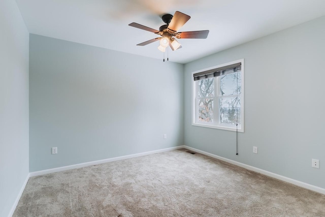 spare room with carpet flooring, ceiling fan, visible vents, and baseboards