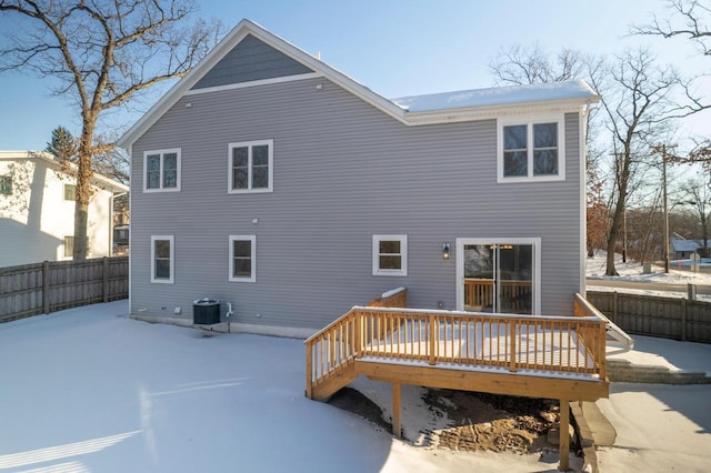 snow covered house featuring fence, a deck, and cooling unit