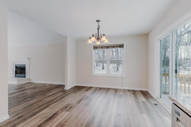 unfurnished dining area featuring wood finished floors, plenty of natural light, and a fireplace