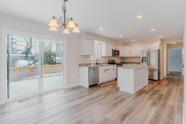 kitchen featuring visible vents, appliances with stainless steel finishes, light wood-style floors, white cabinetry, and a sink