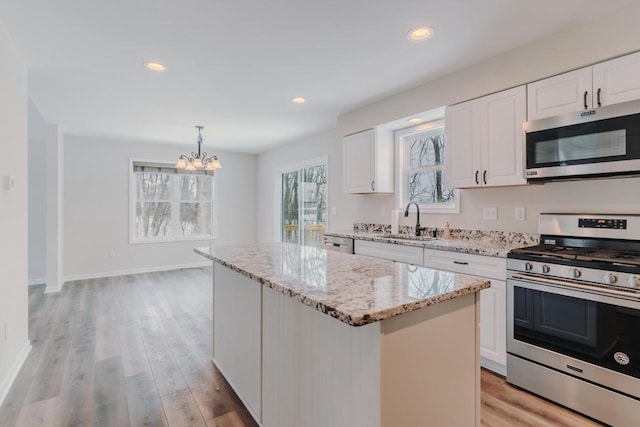 kitchen with light wood-type flooring, stainless steel appliances, a sink, and a center island