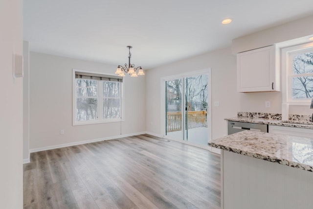 unfurnished dining area with a chandelier, light wood finished floors, recessed lighting, and baseboards