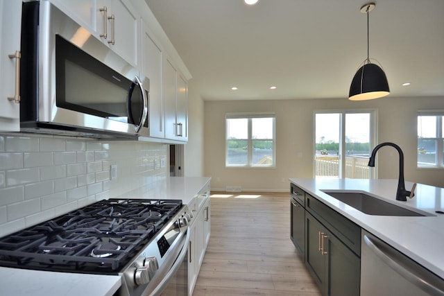 W198N5372 Boxwood Blvd, Menomonee Falls, WI 53051 - kitchen with stainless steel appliances, a sink, light wood-style floors, light countertops, and backsplash