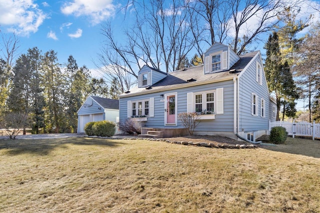 new england style home featuring a detached garage, fence, an outbuilding, and a front yard