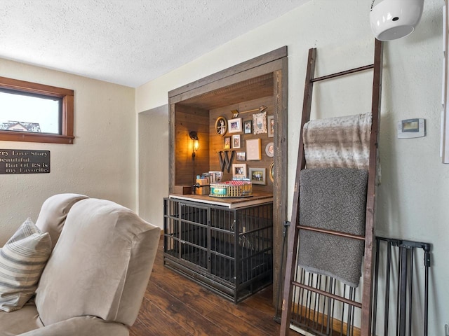 interior space with a textured wall, a textured ceiling, and wood finished floors