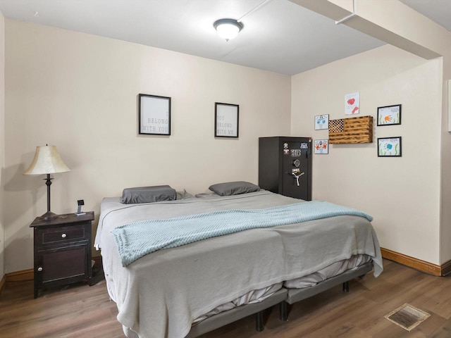 bedroom featuring visible vents, baseboards, and wood finished floors