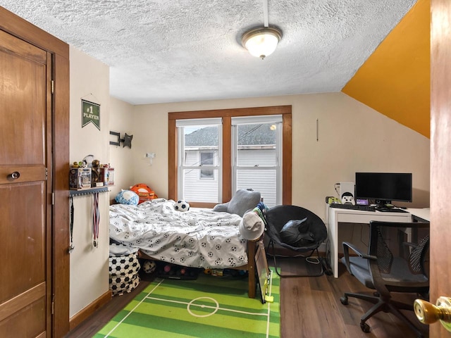 bedroom featuring vaulted ceiling, a textured ceiling, and wood finished floors