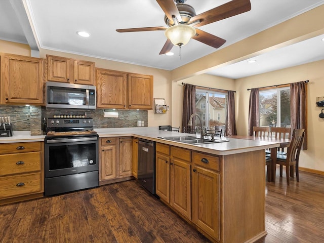 kitchen featuring dark wood finished floors, a peninsula, stainless steel appliances, light countertops, and a sink