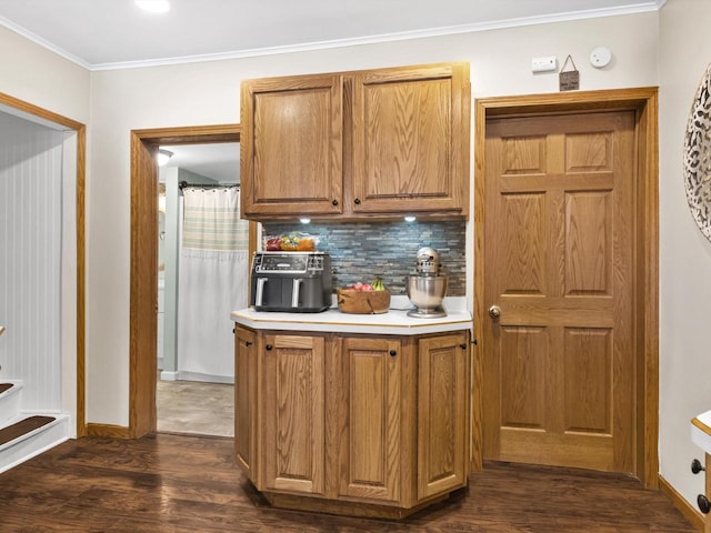 kitchen with light countertops, ornamental molding, dark wood-style flooring, and backsplash