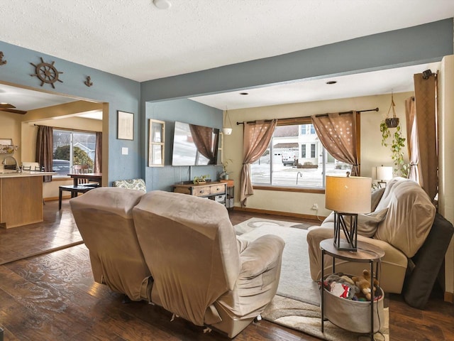 living area with dark wood finished floors, a textured ceiling, and baseboards