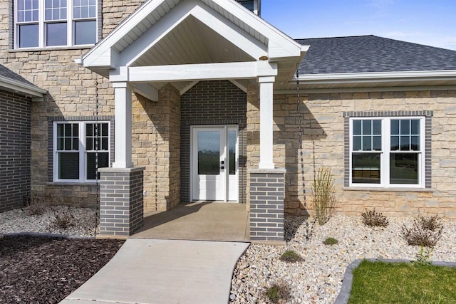 doorway to property with stone siding and roof with shingles