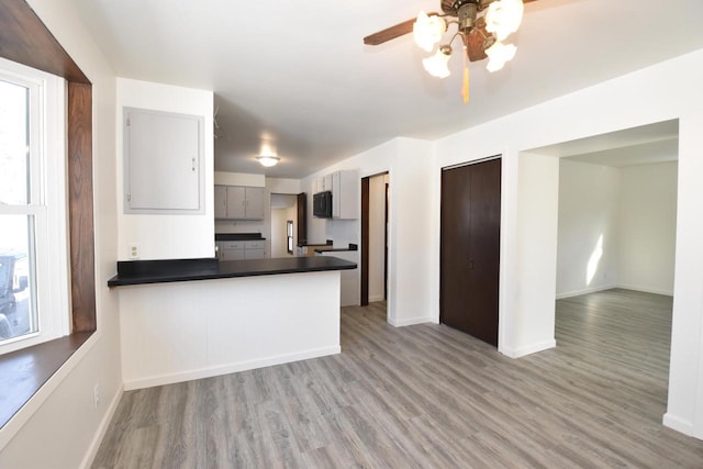 kitchen with dark countertops, light wood-type flooring, black microwave, and gray cabinets