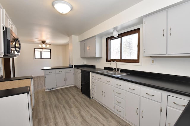 kitchen featuring dark countertops, stainless steel microwave, a sink, dishwasher, and a peninsula