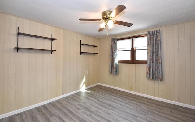 unfurnished room featuring a ceiling fan, baseboards, and wood finished floors