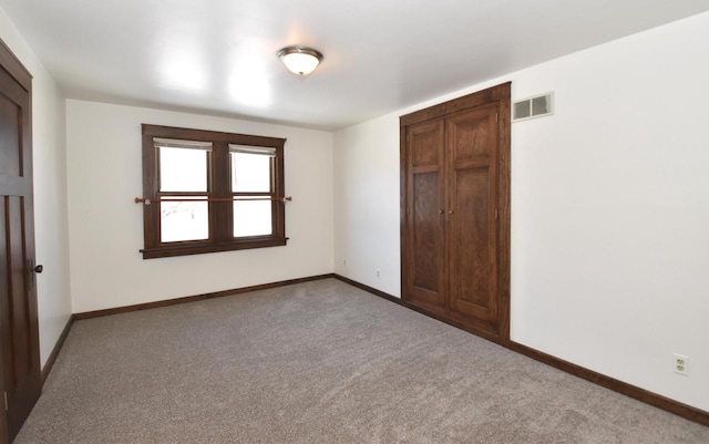 unfurnished bedroom with carpet floors, baseboards, visible vents, and a closet