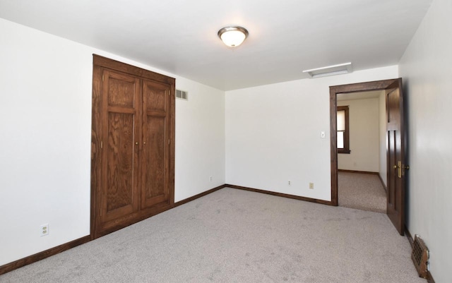 unfurnished bedroom featuring light carpet, baseboards, visible vents, and attic access