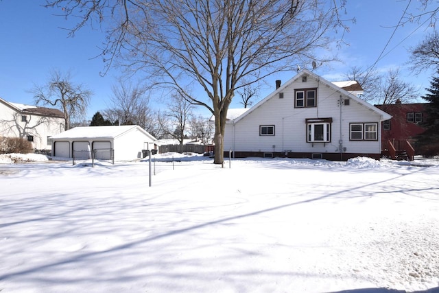 view of snow covered exterior featuring a garage and an outbuilding