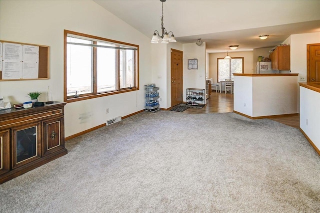 unfurnished living room with visible vents, baseboards, vaulted ceiling, carpet floors, and a notable chandelier