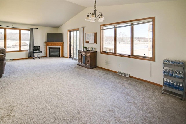 unfurnished living room with visible vents, plenty of natural light, an inviting chandelier, a fireplace, and lofted ceiling