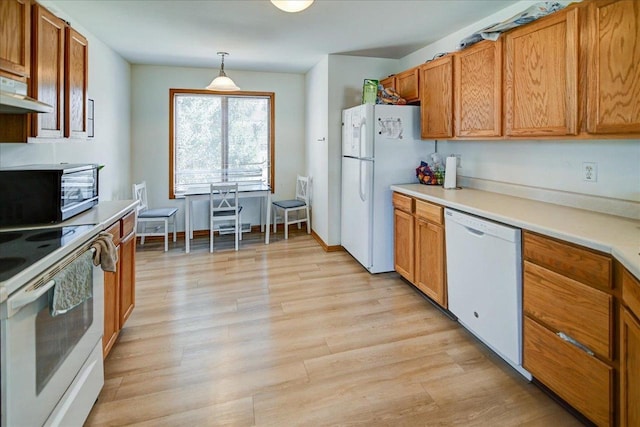 kitchen with brown cabinets, light wood finished floors, decorative light fixtures, white appliances, and light countertops