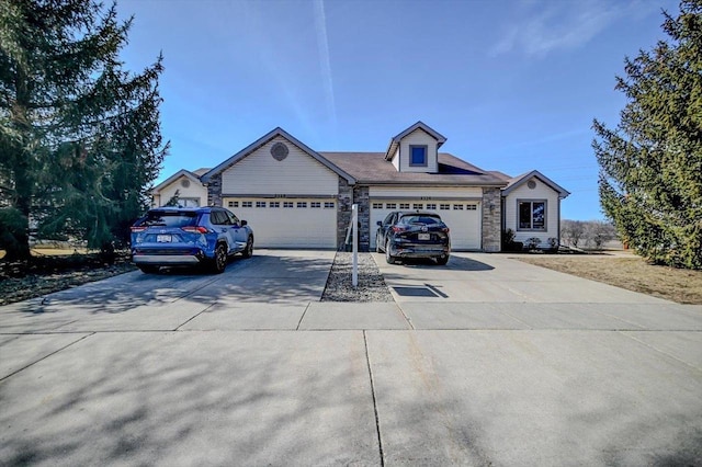 view of front of property featuring an attached garage, stone siding, and driveway