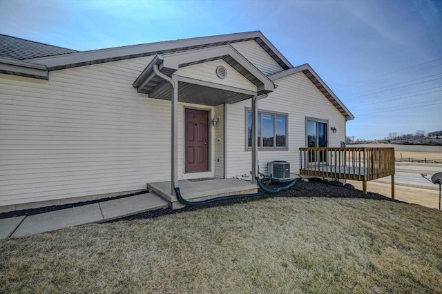 view of exterior entry featuring a lawn and a wooden deck