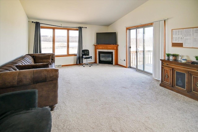 carpeted living area featuring a tiled fireplace, baseboards, and vaulted ceiling