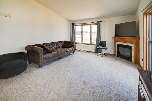 living area featuring visible vents, carpet, baseboards, vaulted ceiling, and a tile fireplace